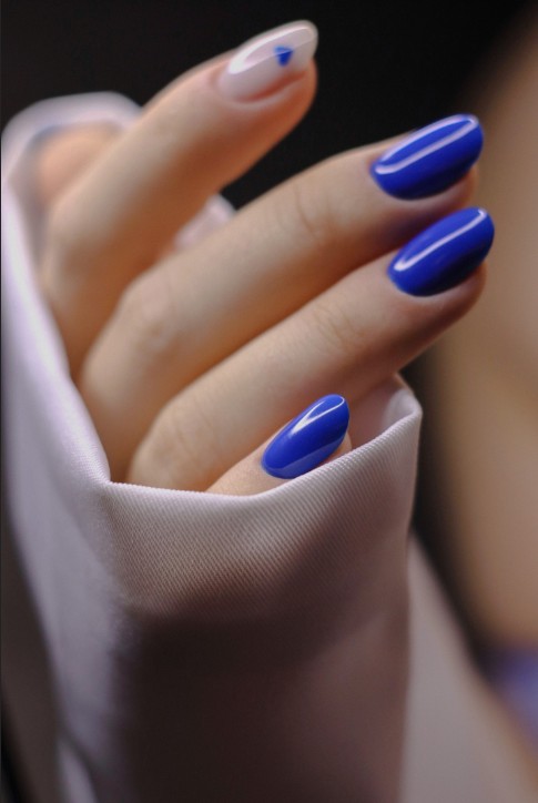 Яркий синий маникюр кобальтового цвета в Архангельске, салон красоты "Мускат". Глянцевый гель-лак на овальных ногтях с акцентом: белая лунка и минималистичный дизайн на безымянном пальце. Модный весенне-летний дизайн.